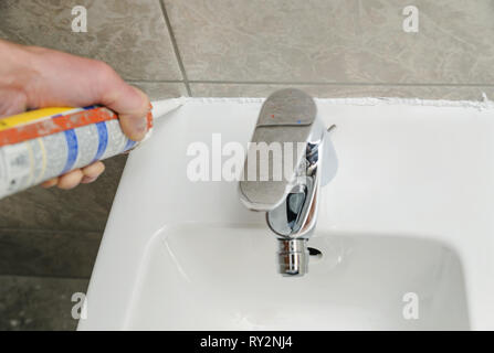 Worker met joint silicone de calfeutrer le joint entre bidet et le mur. Banque D'Images