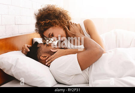 African-American girl kissing her sweetheart au lit Banque D'Images