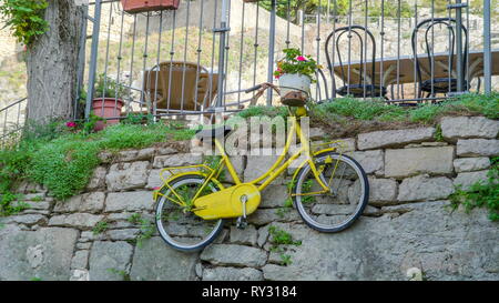 Plus près des pots de fleurs sur le dessus du vélo accroché au mur de la clôture des tours Banque D'Images