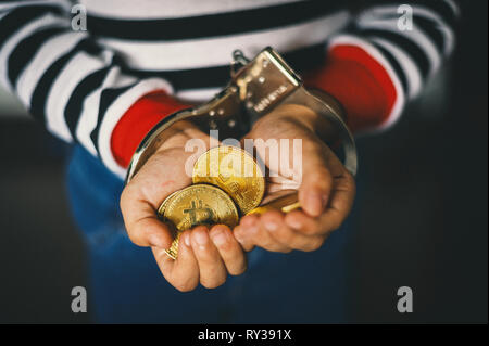 Hand holding golden Bitcoin. L'homme criminel avec des menottes après avoir commis un crime Banque D'Images