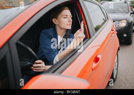 Une femme se sent le stress sur la route. Le fait montre dans la fenêtre. Gros embouteillages. Femme d'affaires est en retard au travail Banque D'Images