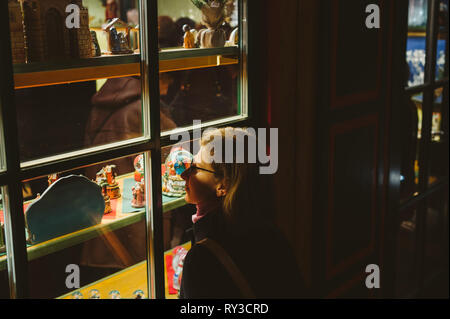 Woman admiring les cadeaux de Noël de souvenirs par les fenêtres du chalet du Marché de Noël à Strasbourg Alsace, atmosphère Banque D'Images