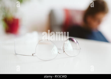 Mince moderne-rim titan optique lunettes lunettes sur table avec femme silhouette de flou artistique en arrière-plan de travail Banque D'Images