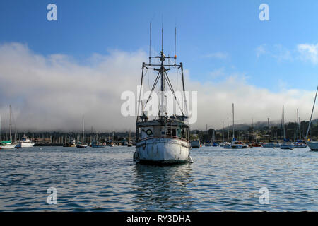 Bateau de taille moyenne avec des antennes radio et de vieux conseils bateau blanc flottant sur l'eau calme dans la baie, vue de sa face avant. Yachts et voiliers amarrés Banque D'Images