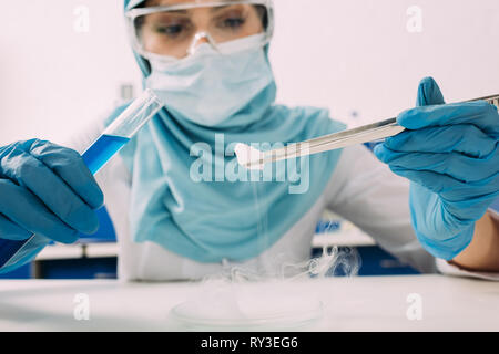 Portrait of female scientist musulmane avec des pincettes et l'essai de laboratoire dans de la glace sèche Banque D'Images