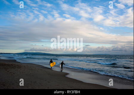 Les surfeurs sur la plage de Santa Monica avec Palos Verdes Peninsula en arrière-plan à Los Angeles, CA. Banque D'Images