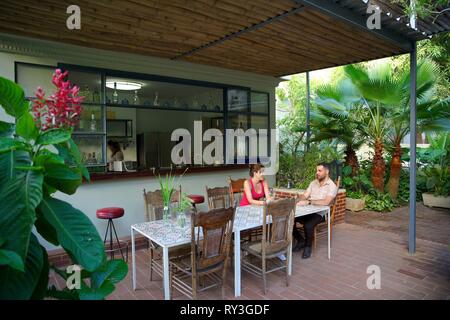 Cuba, La Havane, Vedado, couple assis devant le bar de la maison d'hôtes de luxe la Reserva au milieu d'un jardin tropical Banque D'Images