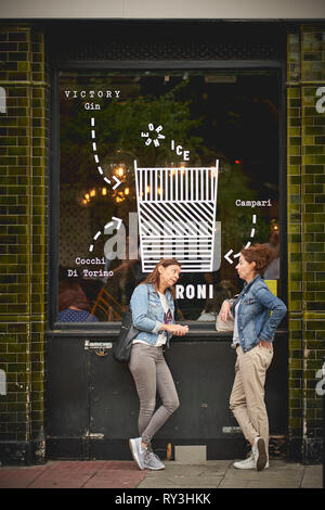 Londres, UK - août 2018. Deux jeunes filles boire une bière à l'extérieur d'un pub à Columbia Road, près de Shoreditch. Banque D'Images