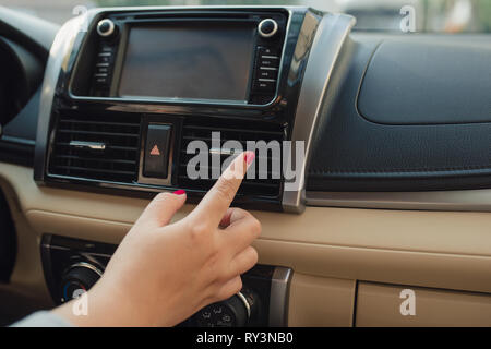 Femme allume la climatisation dans la voiture. Intérieur voiture moderne Banque D'Images