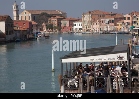 Les personnes mangeant à l'extérieur, au soleil le long du canal principal d'Murano, Murano, Venise Italie Banque D'Images