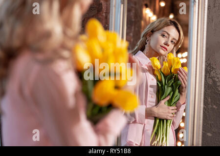 Appel woman wearing pink blouse holding fleurs jaunes Banque D'Images