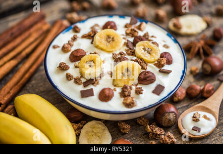 Servant de yaourt blanc avec du muesli, banane et noix Banque D'Images