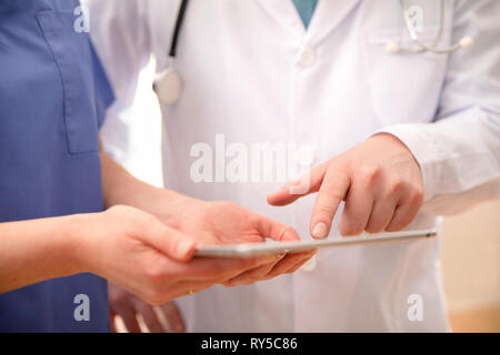 Doctor and nurse discussing patients essais a tablet computer in hospital Banque D'Images