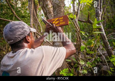 La Dominique, un guide présente un signe indiquant une forte montée en épingle à cheveux se penche sur l'article 1 de la Sentier de randonnée Waitukubuli qui traverse l'île Banque D'Images