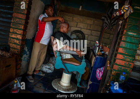 Un Colombien coiffure coupe de cheveux d'un homme dans une boutique de coiffeur dans le marché d'Bazurto, Cartgena, Colombie, 17 avril 2018. Banque D'Images