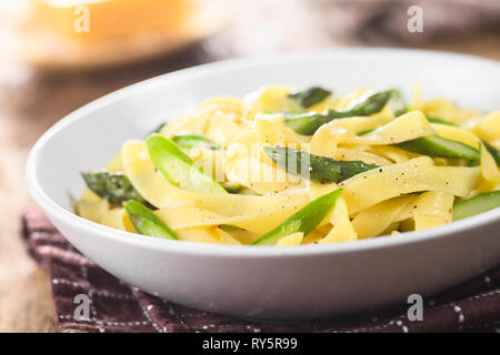 Des pâtes fraîches plat de fettucine ou tagliatelle, asperges vertes, l'ail et le jus de citron dans un bol, de poivre noir sur le dessus Banque D'Images