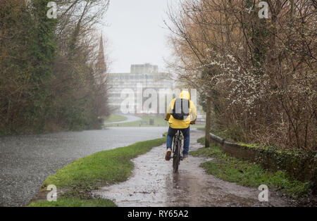 Kidderminster, Royaume-Uni. 12 mars 2019. Météo au Royaume-Uni : de fortes pluies dans tout le Royaume-Uni laissent certains navetteurs trouver le chemin un peu difficile! Un cycliste isolé, dans une veste jaune haute visibilité, vu de derrière lui, parcourt un chemin de remorquage de canal incapable d'éviter la formation de flaques boueuses alors que la pluie torrentielle persiste. Credit Lee Hudson/Alay Live News Banque D'Images