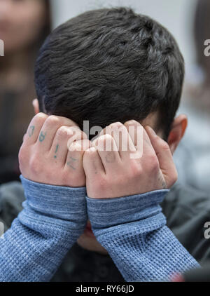 Wiesbaden, Allemagne. Mar 12, 2019. Le défendeur Ali B. couvre son visage au début de l'essai. La cour criminelle accuse le réfugié de l'Iraq d'avoir violé et assassiné 14 ans Susanna de Mayence en mai dernier. Après sa fuite à l'Iraq, l'auteur allégué a été ramené à l'Allemagne quelques jours plus tard. Credit : Boris Roessler/apd extérieure/dpa/Alamy Live News Banque D'Images