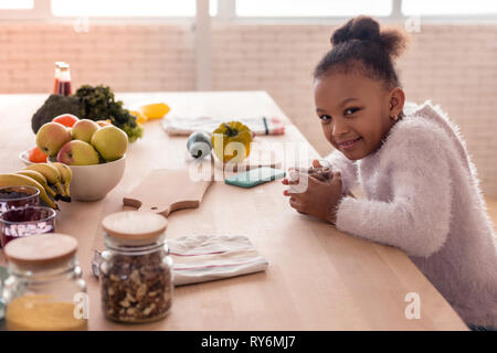 Cute girl ayant délicieux petit déjeuner avant d'aller à l'école maternelle Banque D'Images