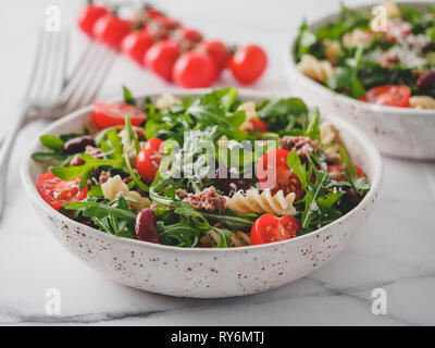 Salade de thon, tomates, roquette, haricot rouge, des pâtes. Idée et recette pour un déjeuner ou dîner. Deux bols à salades chaudes sur la table de marbre. Idées et recettes pour dîner ou déjeuner sain Banque D'Images