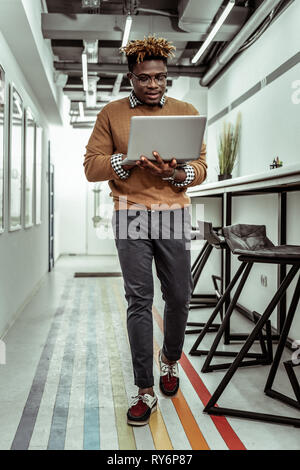 L'homme porté à la peau sombre avec funky hairstyle déménagement autour avec portable Banque D'Images