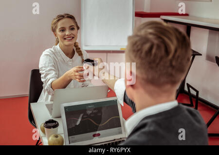 Courte généreux brun propose son café dans la coupe en carton à smiling woman Banque D'Images