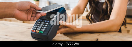 Portrait de caissier, debout près de comptoir bar et la tenue de payer avec l'homme terminal smartphone wile dans coffee house Banque D'Images