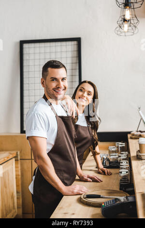 Les caissiers standing and smiling derrière barre en bois dans coffee house compteur Banque D'Images