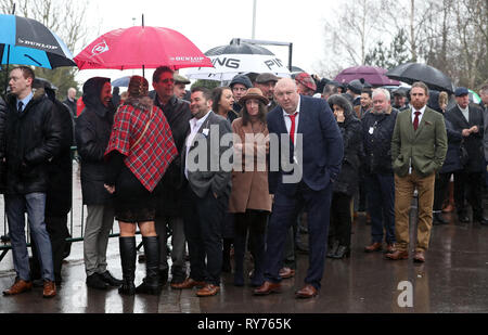 Racegoers abri de la pluie pendant qu'ils attendent pour les portes à ouvrir pour défendre jour de la Cheltenham Festival 2019 à l'Hippodrome de Cheltenham. Banque D'Images