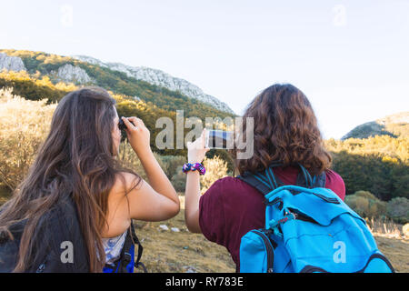 Vue arrière des randonneurs avec des sacs à dos à la montagne, à l'encontre de ciel clair Banque D'Images