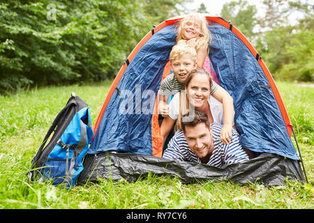 Famille heureuse avec deux enfants dans la tente en camping en vacances Banque D'Images