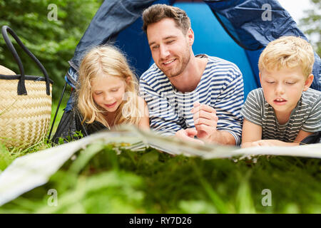 Le père et les deux enfants ensemble dans une tente en camping en vacances d'été Banque D'Images