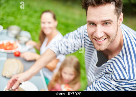 L'homme et de la famille de prendre le petit déjeuner dans le jardin ou le camping en été Banque D'Images