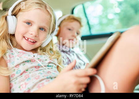 Frères et sœurs des enfants dans la voiture à écouter de la musique avec des écouteurs comme streaming en ligne Banque D'Images