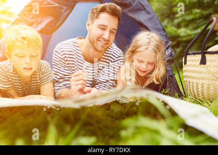 Le père et les enfants sont en regardant une carte devant une tente en camping dans la nature Banque D'Images