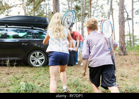 Deux enfants avec raquettes de badminton courir à la voiture avant de partir en vacances Banque D'Images