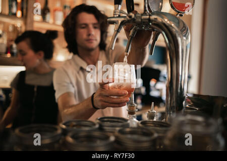 Bartender mixing drinks derrière un comptoir bar de nuit Banque D'Images