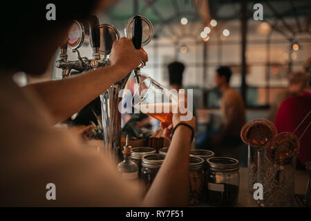 Bartender pouring beer derrière un comptoir bar de nuit Banque D'Images