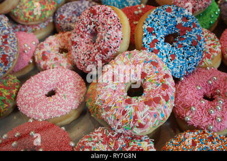 Tant de donuts couverts avec du glaçage et des sucres colorés Banque D'Images