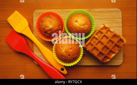 Simple mini muffins en silicone colorés à cuisson. Coupelle en silicone baking cupcakes et pinceaux en silicone. Concept de cuisine et cuisine sur fond de bois Banque D'Images