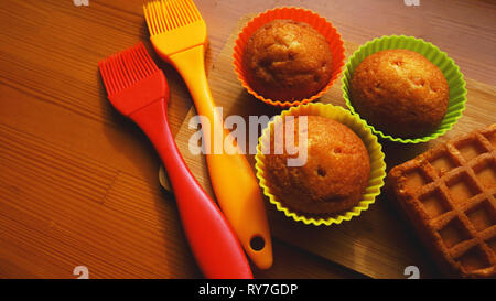 Simple mini muffins en silicone colorés à cuisson. Coupelle en silicone baking cupcakes et pinceaux en silicone. Concept de cuisine et cuisine sur fond de bois Banque D'Images