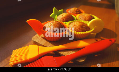 Simple mini muffins en silicone colorés à cuisson. Coupelle en silicone baking cupcakes et pinceaux en silicone. Concept de cuisine et cuisine sur fond de bois Banque D'Images