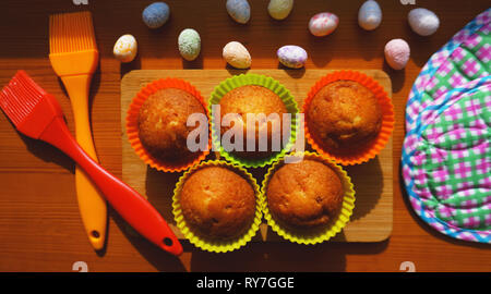 Minis gâteaux décorés avec des oeufs de Pâques, un dessert. Simple mini muffins en silicone colorés à cuisson. Concept de cuisine et cuisine sur fond de bois Banque D'Images
