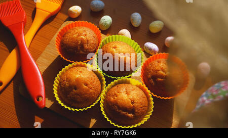 Minis gâteaux décorés avec des oeufs de Pâques, un dessert. Simple mini muffins en silicone colorés à cuisson. Concept de cuisine et cuisine sur fond de bois Banque D'Images