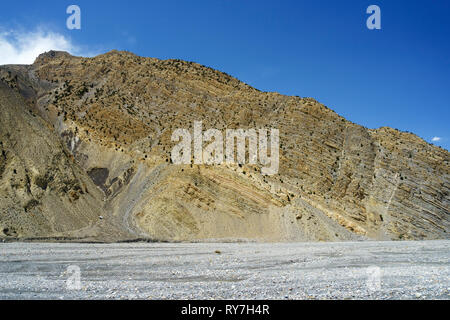 Rocky hill avec géologiques visibles stratas surplombant la rivière à sec de la Kali Gandaki entre Jomsom et Kagbeni, Upper Mustang région, le Népal. Banque D'Images