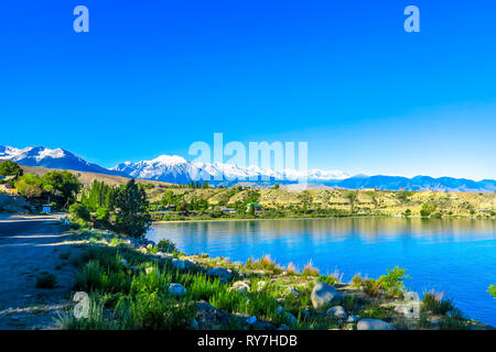 Rive du lac Issyk Kul rochers en pierre de sable avec enneigés des montagnes du Tian Shan Banque D'Images