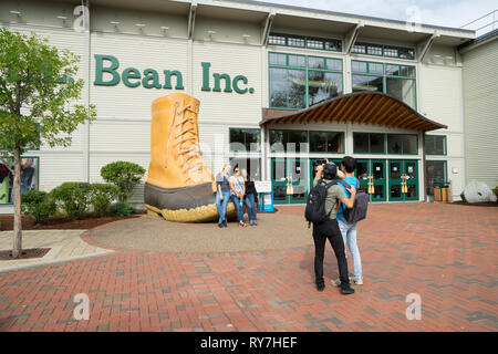 Les visiteurs qui prennent une photo souvenir avec le 90e anniversaire d'amorçage bean en face de LL Bean store à Freeport, Maine, USA. Banque D'Images