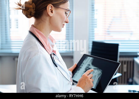 Doctor looking at x-ray photo d'une épaule sur sa tablet computer Banque D'Images