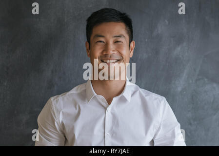 Content Asian businessman standing in front of a blank chalkboard Banque D'Images