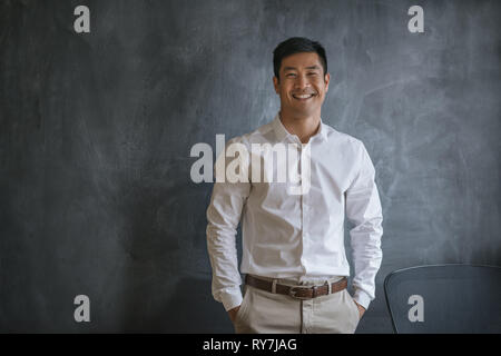 Rire Asian businessman standing in front of a blank chalkboard Banque D'Images